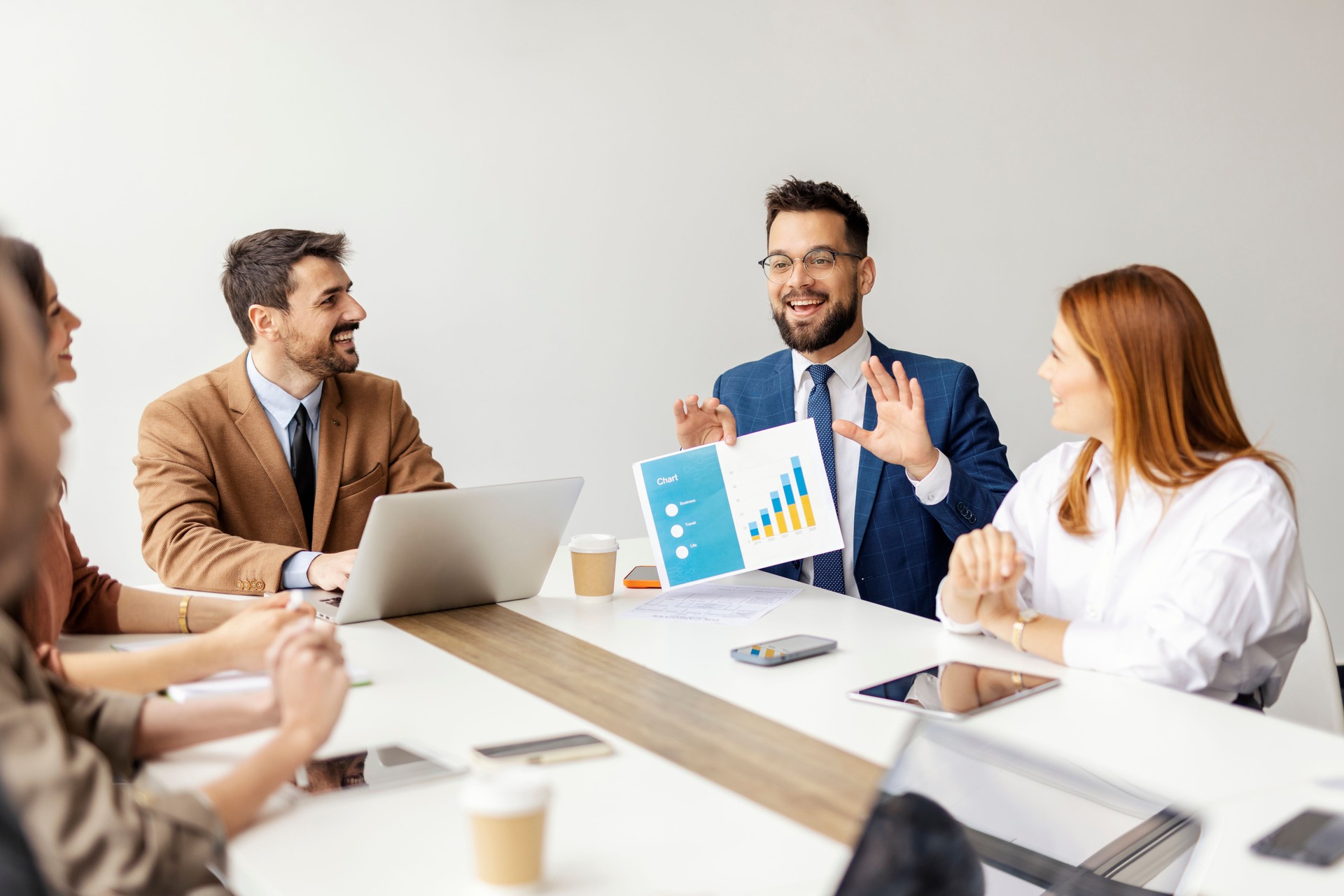 Businessman sitting at conference room with his team and showing chart and documents.