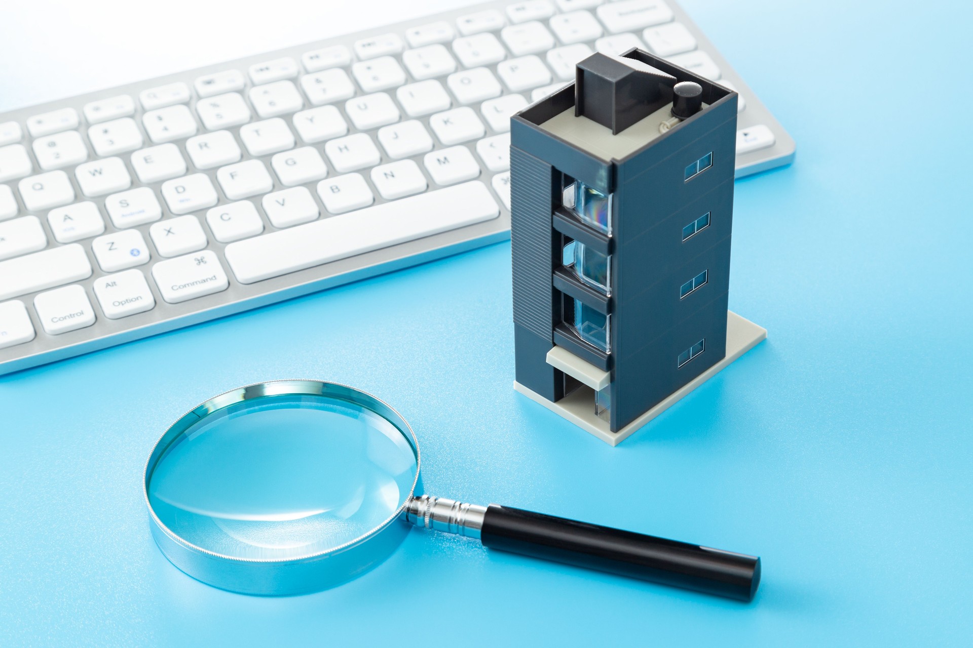 A building model, a computer keyboard and a magnifying glass.